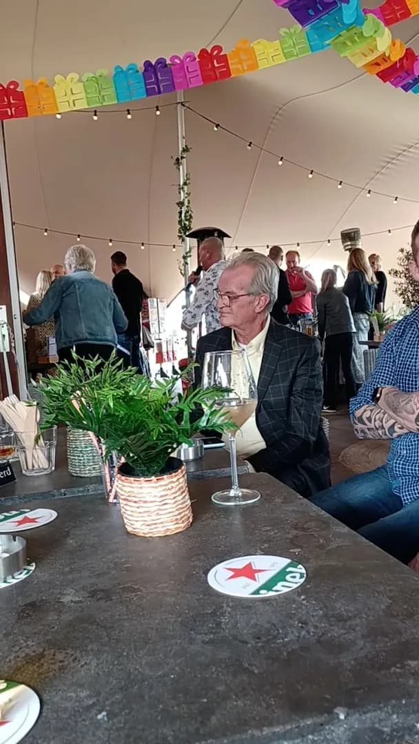 Gasten aan een feesttafel onder slingers