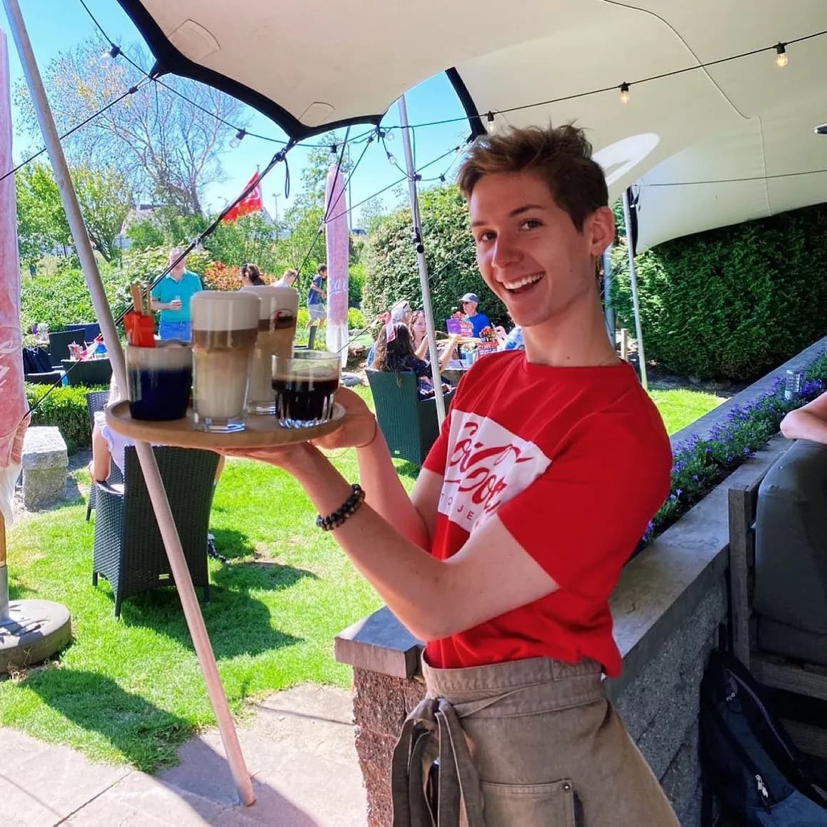 Medewerker met een dienblad koffie op het terras
